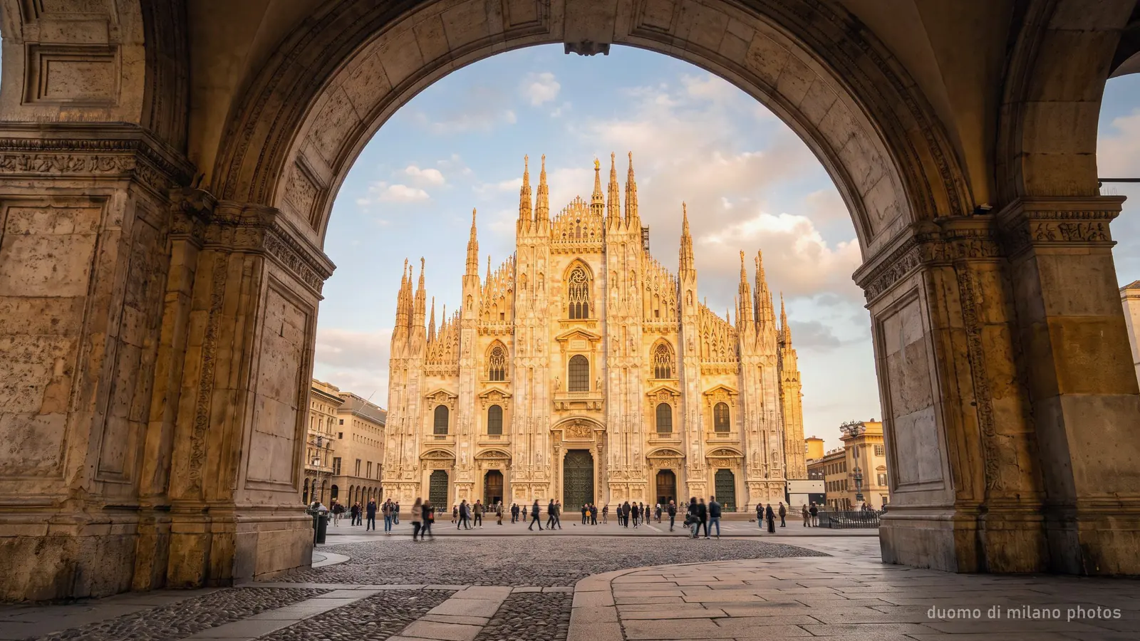 The Duomo di Milano photographed through a stone arch at golden hour